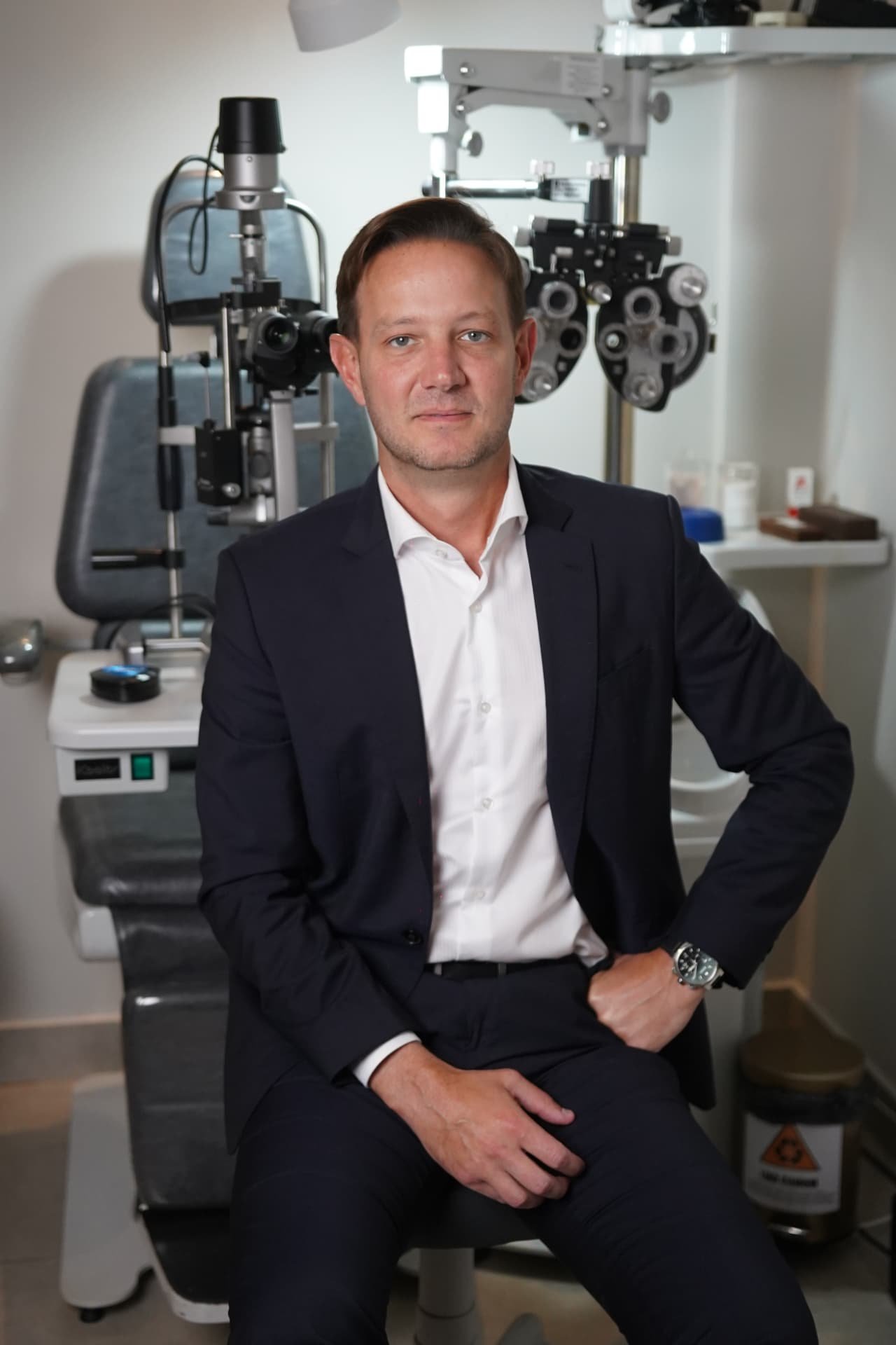 Dr. Filipe Gasparin ao lado dos equipamentos de exame oftalmológico